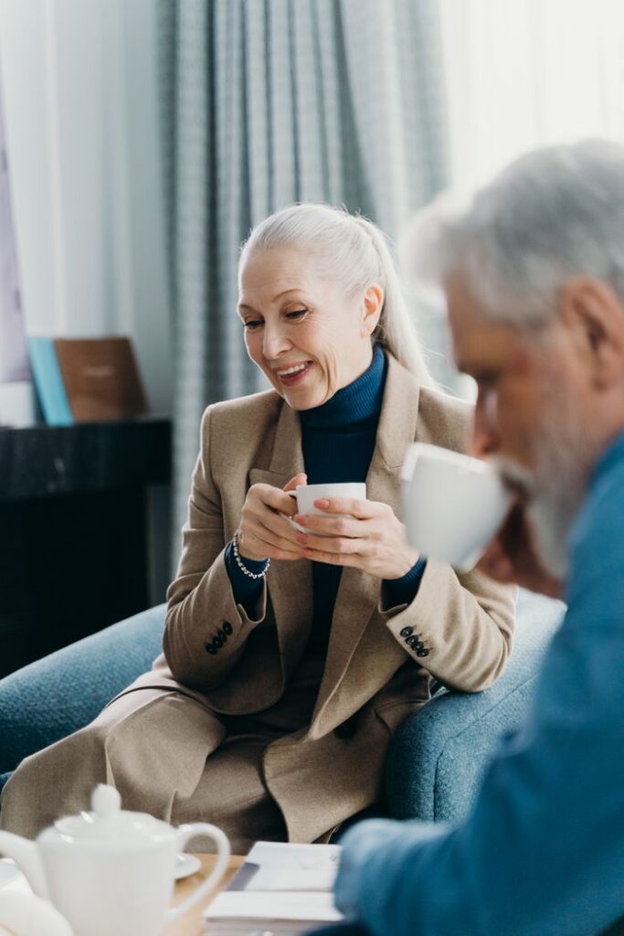 Senior adults sitting indoors, warmly engaged over coffee in a cozy, relaxed atmosphere.